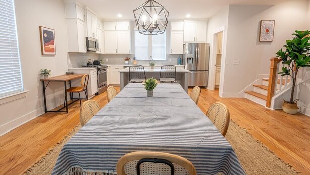 Una cocina moderna con armarios blancos, una isla central y un comedor con mantel a rayas.
