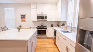 Una cocina moderna con armarios blancos, electrodomésticos de acero inoxidable y suelo de madera.