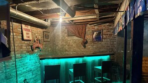 Un espace bar avec un panneau indiquant qu’il est interdit de se garer, une enseigne Bud Light et une fresque sur le mur de briques.