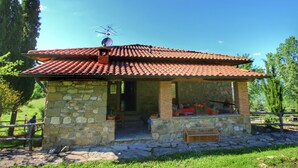 A stone house with a tiled roof, a wooden bench, and potted plants. - Rustic Holiday Home in Ortignano With Swimming Pool (Ortignano Raggiolo)