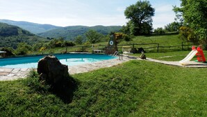 A swimming pool with a stone clock tower, surrounded by a wooden fence and a slide. - Rustic Holiday Home in Ortignano With Swimming Pool (Ortignano Raggiolo)