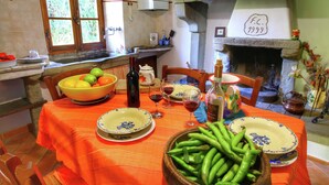 A dining table set with plates, bowls, and bottles, a window with curtains, and a fireplace with a date plaque. - Rustic Holiday Home in Ortignano With Swimming Pool (Ortignano Raggiolo)