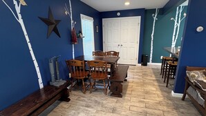 A dining area with a wooden table and chairs, a bench, and a decorative wall with a star and tree branches. - Charming 2-bedroom apartment in superb Bennington with WiFi (Bennington)