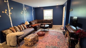 A living room with a sectional sofa, ottomans, a coffee table, and a patterned rug. - Charming 2-bedroom apartment in superb Bennington with WiFi (Bennington)
