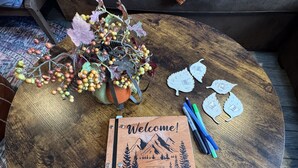 A round wooden coffee table with a 'Welcome!' sign, a notebook, markers, and decorative leaves. - Charming 2-bedroom apartment in superb Bennington with WiFi (Bennington)