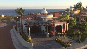 Una propiedad costera con una estructura cúpula central, un porche cubierto y un camino de acceso curvo que conduce a una entrada con portón.