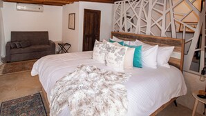 A bedroom with a large bed, a wooden headboard, a brown sofa, and a patterned rug. - Aria Boutique BY LD Hoteles (Maneiro)