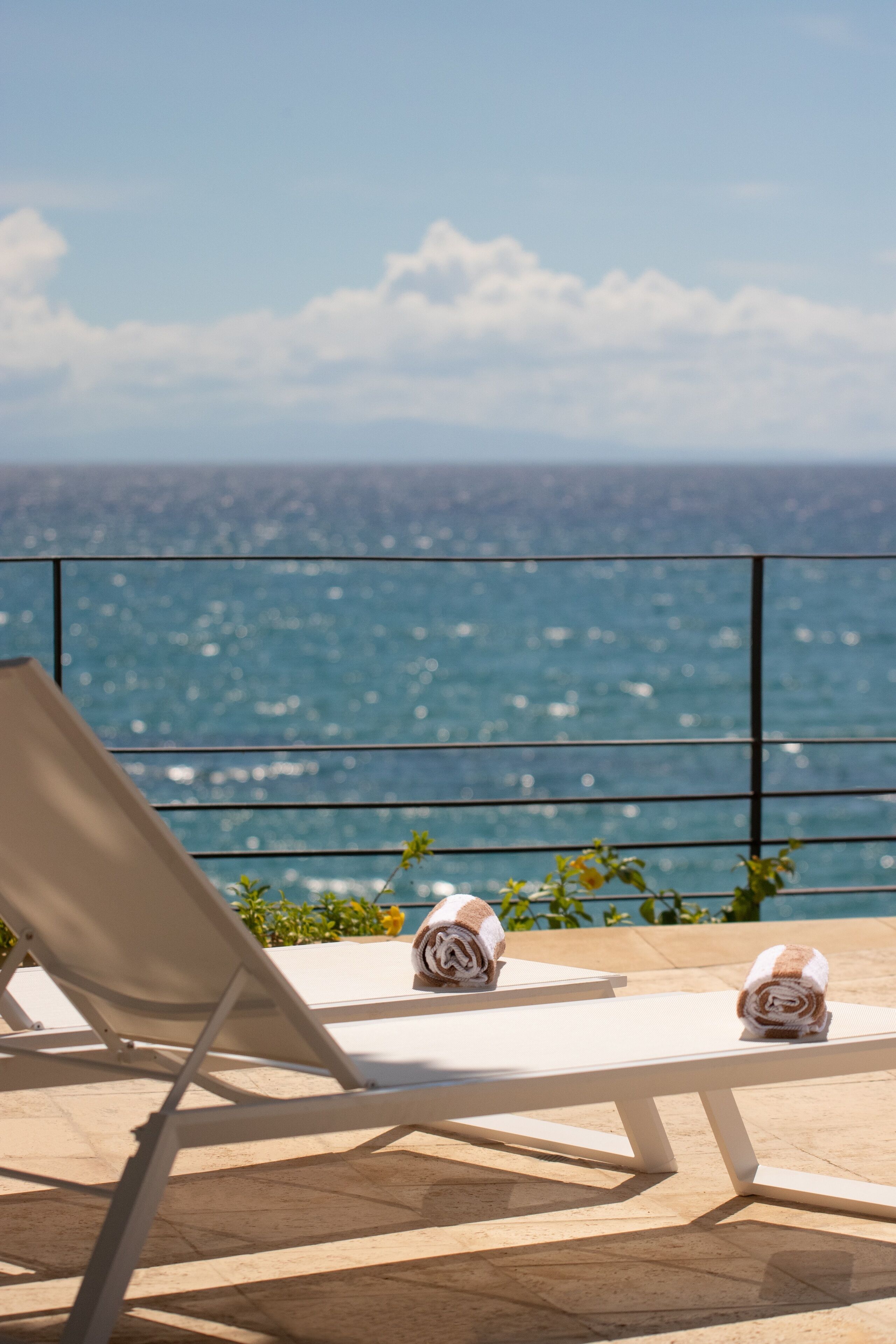 Een balkon met twee witte loungestoelen en uitzicht op zee.