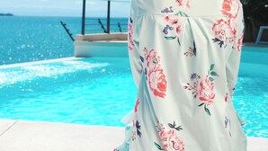 A person sitting by a pool with a clear view of the ocean and palm trees. - Aria Boutique BY LD Hoteles (Maneiro)