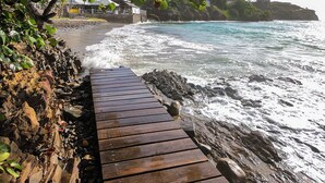 A wooden boardwalk leading to a beach with waves crashing onto the shore. - Aria Boutique BY LD Hoteles (Maneiro)