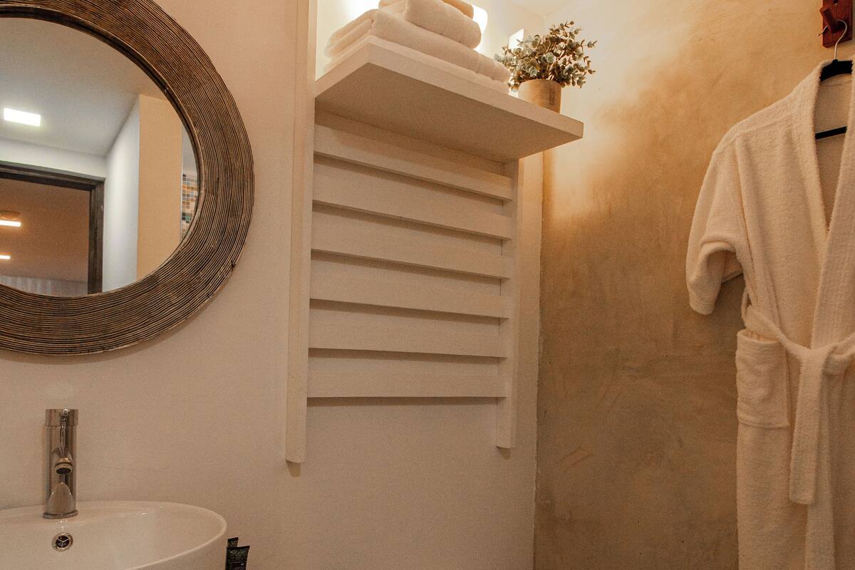 A bathroom with a round mirror, a sink, a toilet, and a towel rack.