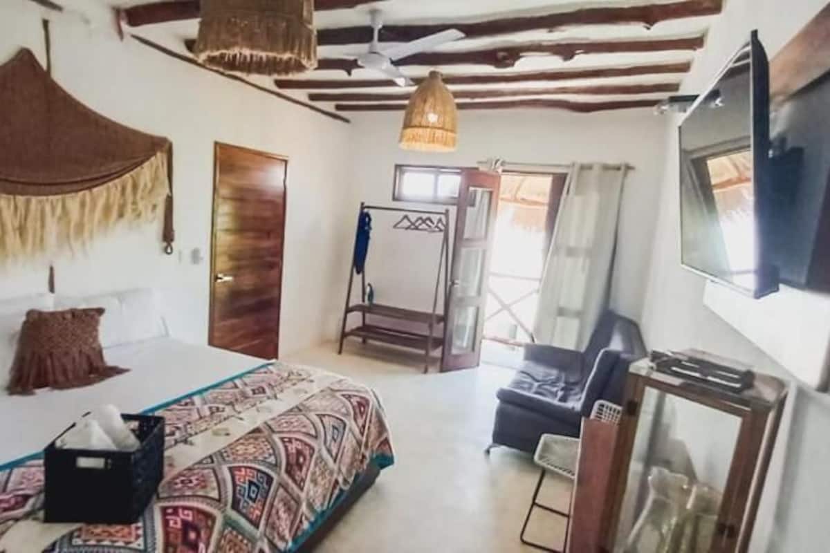 Une chambre à coucher avec un lit, une télévision, un ventilateur de plafond et une fenêtre.