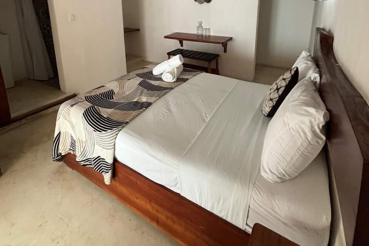 Une chambre à coucher avec un lit, une table de chevet, un miroir et un téléviseur fixé au mur.