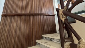 Un mur recouvert de panneaux de bois, un escalier orné de carreaux décoratifs et une main courante en bois.