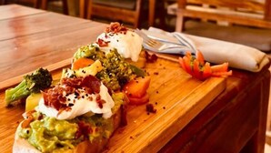Une table en bois avec un plat de nourriture, et en arrière-plan, une enseigne portant les inscriptions « BOCAMAR » et « MARISCUEÑA & PACÍFICO ».
