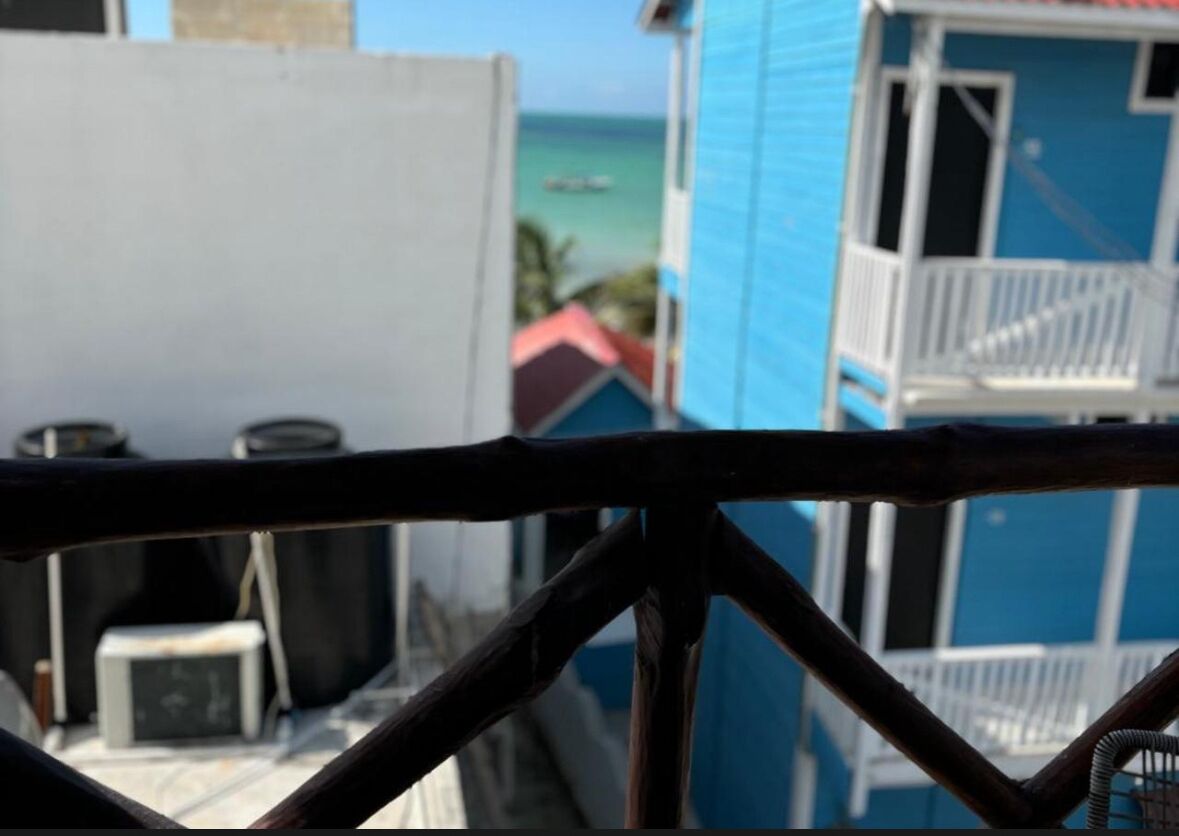 Un balcón con vista al océano y un edificio de fachada azul.