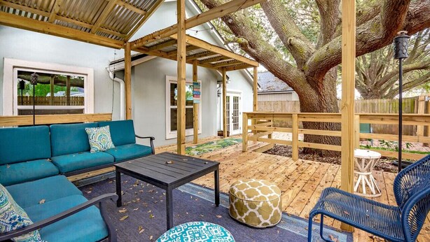 An outdoor patio with a wooden pergola, a blue sofa, a small table, and a blue chair. - Entire JAX Beach Bungalow 7 blocks from Ocean (Jacksonville Beach)