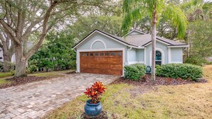 A single-story house with a garage, surrounded by mature trees and a well-maintained lawn. - Entire JAX Beach Bungalow 7 blocks from Ocean (Jacksonville Beach)