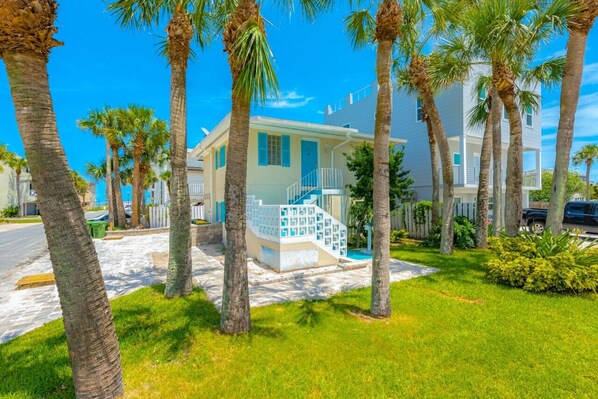 A two-story house with a light blue exterior, a white front porch, and a staircase leading to the entrance.