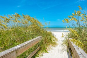 A wooden pathway leading to a beach with clear blue skies.