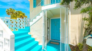 A building with turquoise steps leading to a white door marked "2103".