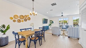 A spacious living area with a dining table, chairs, and a striped sofa. - *Brand New* Family Home, Steps From the Sand (Jacksonville Beach)