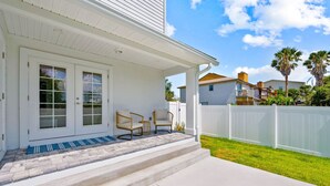 A white house with a covered porch, two wicker chairs, and a white fence. - *Brand New* Family Home, Steps From the Sand (Jacksonville Beach)