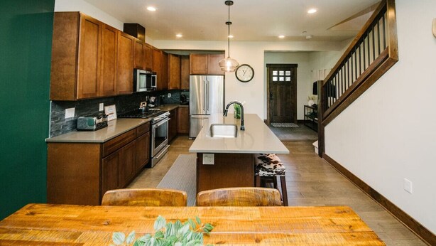 A modern kitchen with wooden cabinets, a central island, and a dining area with a wooden table.