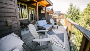 A wooden deck with Adirondack chairs, a sofa, and a dining table.