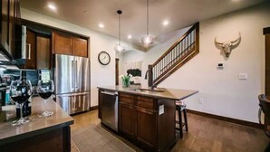 A kitchen with wooden cabinets, stainless steel appliances, and a central island with bar stools.