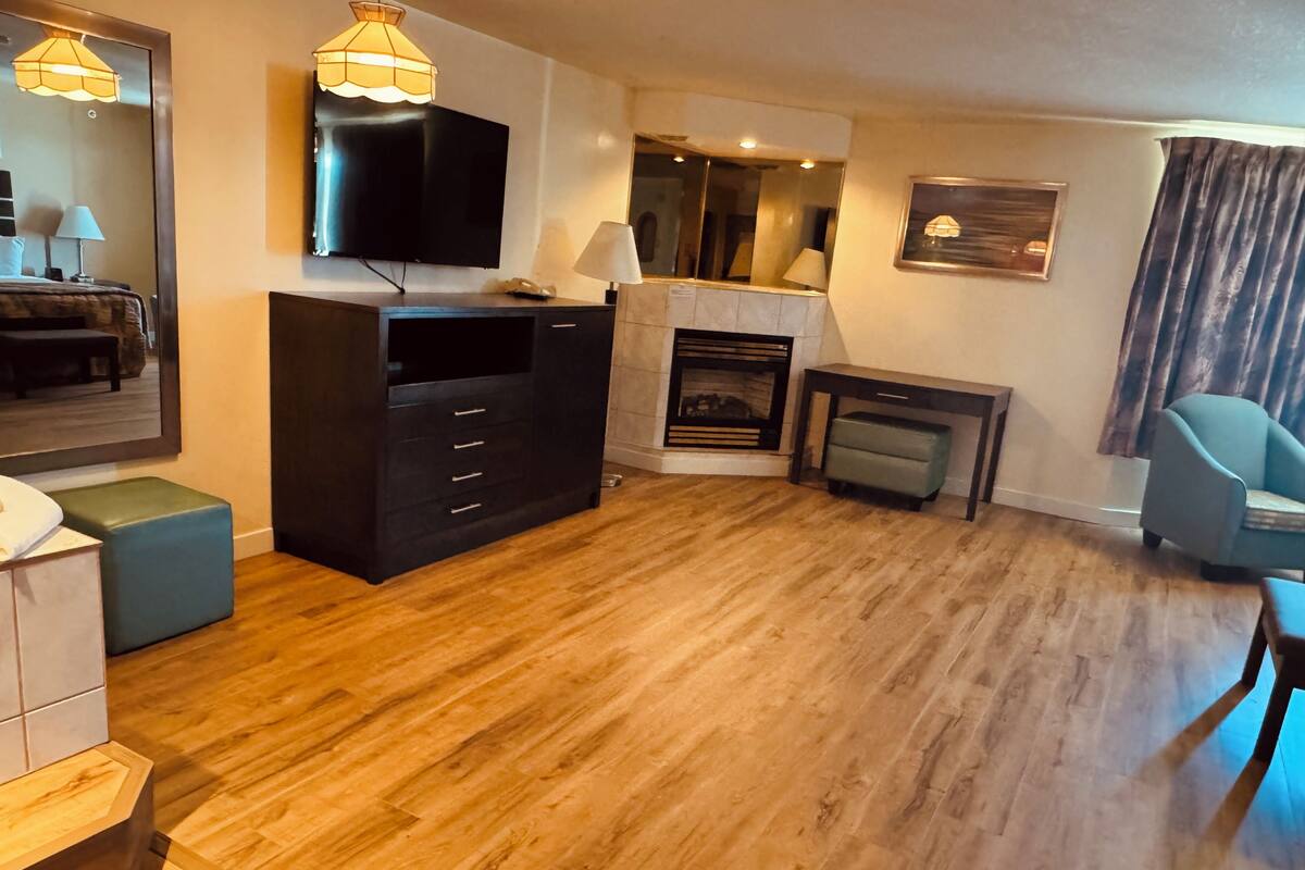 Ein modernes Wohnzimmer mit Flachbildfernseher, Kamin und blauem Sessel.
