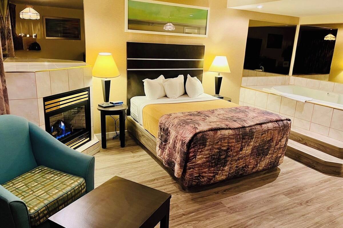 Ein Hotelzimmer mit Bett, Nachttischlampen, Kamin, Sofa und einem kleinen Tisch.