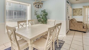 A dining area with a wooden table and chairs, a chandelier, a potted plant, and a view of the living room with a sofa. - < 1 Mi to Ocean: North Myrtle Beach Home w/ Grill! (North Myrtle Beach)