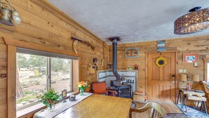 Un interior rústico de madera con una gran mesa de comedor, una chimenea y vistas al exterior.