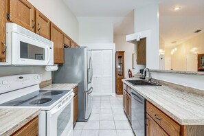 A kitchen with wooden cabinets, a white refrigerator, a microwave, a stove, and a sink. - Fish, Surf & Sun! Charmer 5 Mi to Neptune Beach (Jacksonville)
