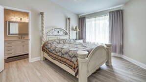 Un dormitorio con una cama grande, un tocador con espejo y una araña.