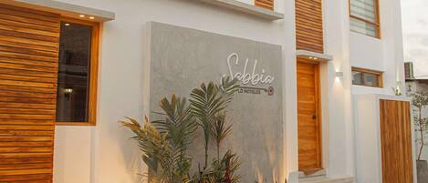 A modern hotel with a flat roof, large windows, and a sign reading "Sabia LO HOTELES".