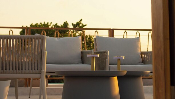 An outdoor seating area with a sofa and chairs, a small table, and a wooden structure. - Sabbia By LD Hoteles (Los Roques)