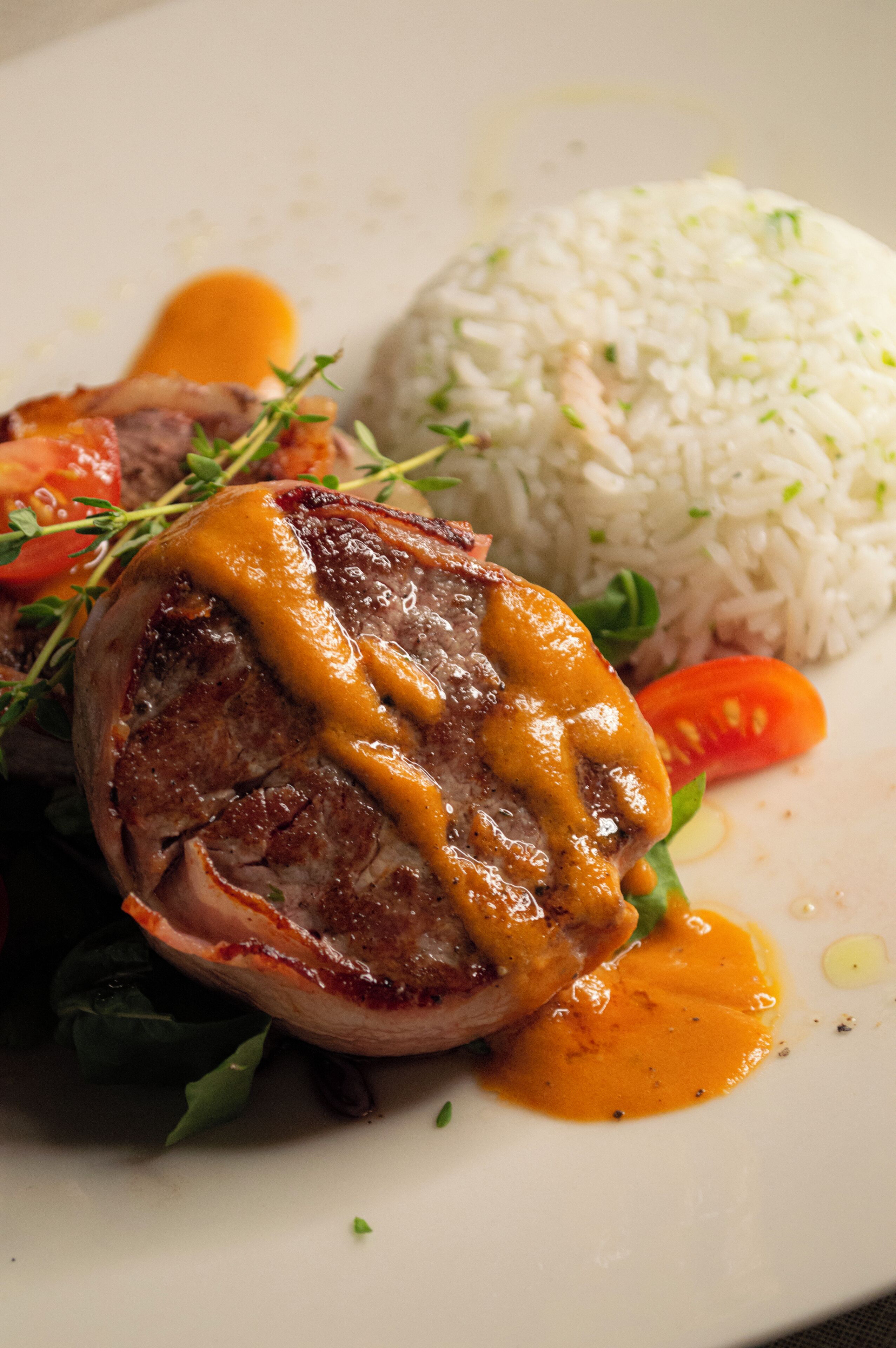 A plate with a grilled meat topped with sauce, rice, and vegetables.
