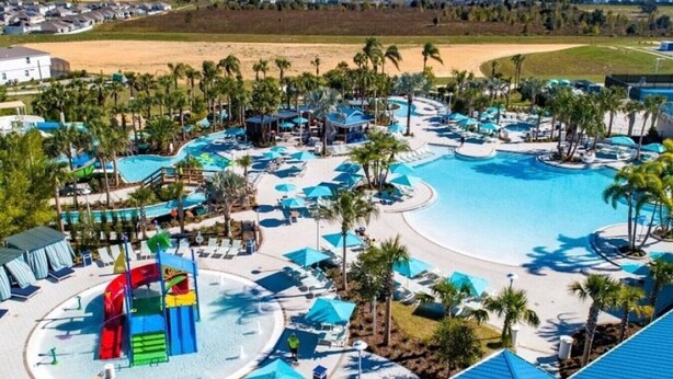 Un resort con una gran piscina, toboganes acuáticos y palmeras.