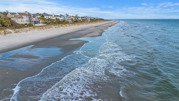 Ein Anwesen direkt am Strand mit Sandstrand, Meerblick und Häusern im Hintergrund.