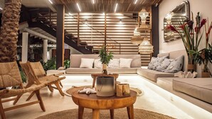 Een moderne woonkamer met een bank, stoelen, een salontafel en een decoratieve plant.