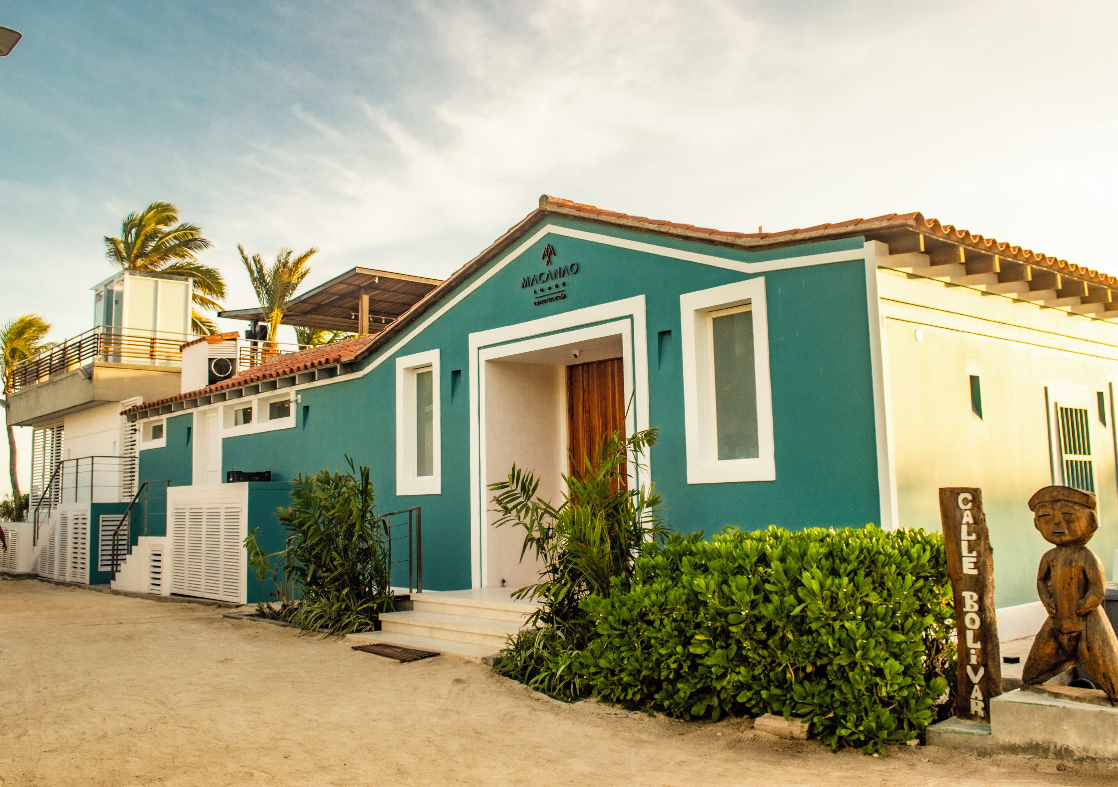 A building with a teal facade, a wooden door, and a sign reading "Calle Bolivar."