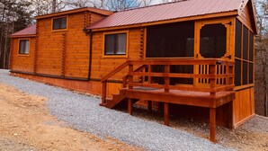 Eine Holzhütte mit einem Metalldach, einer Veranda und einer Schotterauffahrt.