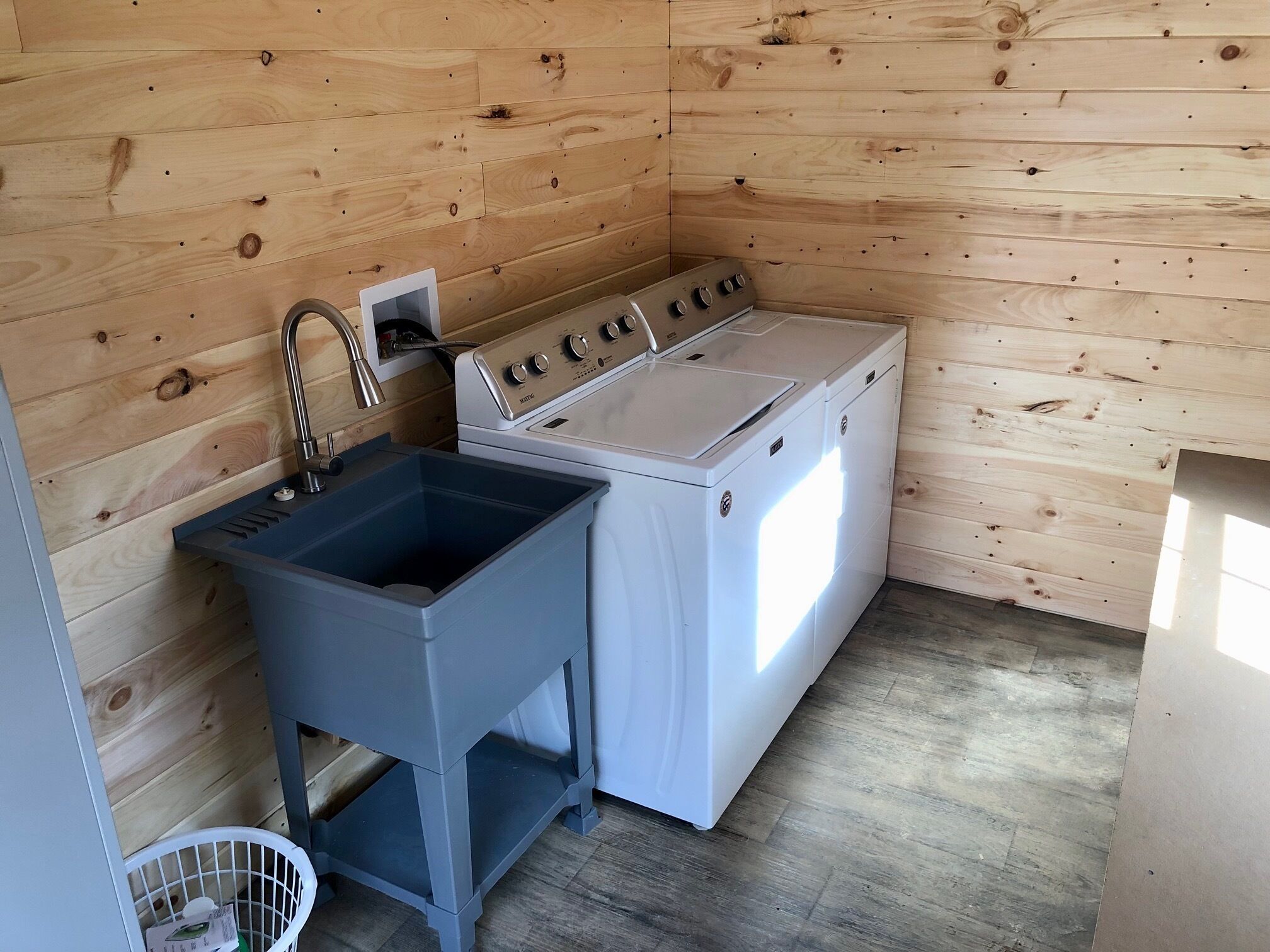 A compact kitchen with wooden walls, a sink, and a stove.