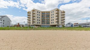 Un hôtel à plusieurs étages, doté d’un toit plat, situé sur une plage de sable.