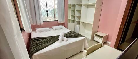 A neatly arranged bedroom with a bed, a bedside table, a wardrobe, and a window with curtains.
