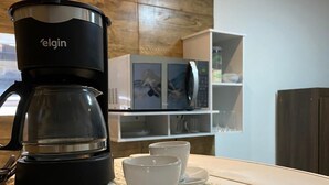 Een moderne keuken met een koffiezetapparaat op het aanrecht, een magnetron en een plank met keukengerei.