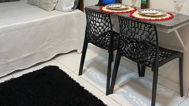 Een slaapkamer met een bed, een bureau met een laptop en een eettafel met een fles en glazen.