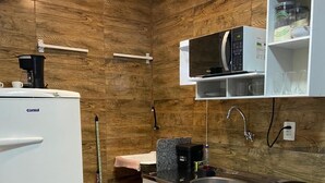 Een kleine keuken met een koelkast, magnetron en wastafel.